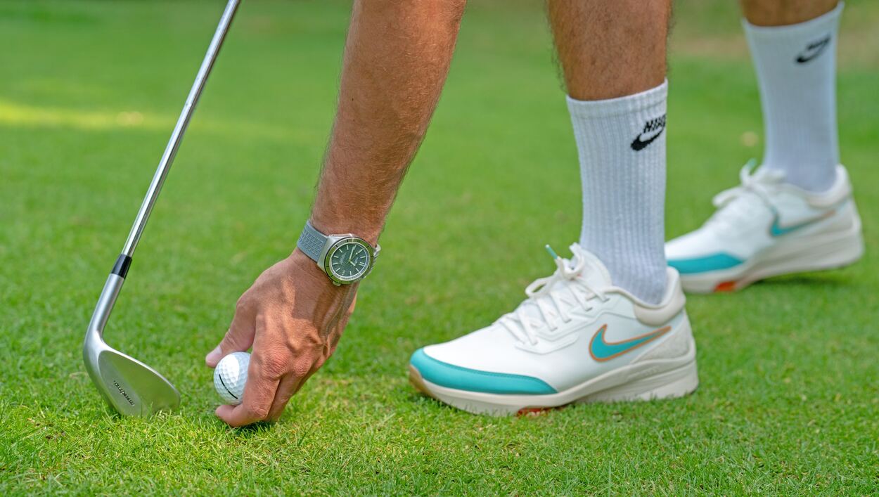 A closer look to a golfer wearing white shoes and white socks placing his golf ball near his golf club.